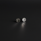 A pair of small round stud earrings with a hammered silver finish, displayed on a dark, reflective surface.