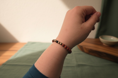 Hand wearing a beaded bracelet with a blurred background
