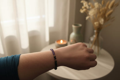 "Woman’s wrist wearing the Obsidian Dawn Bracelet by Jewellery by JN, with amethyst, grey volcanic rock, and silver accent beads."

