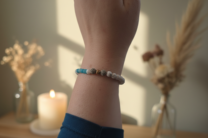 "Woman’s wrist wearing the Truthweaver Bracelet by Jewellery by JN, with blue agate, howlite, grey volcanic rock, and silver accent beads."