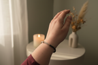 Woman’s wrist wearing the Shadowseer Bracelet by Jewellery by JN, with labradorite, volcanic rock, and silver accent beads.