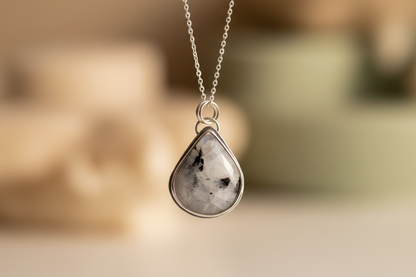 Teardrop-shaped pendant necklace on a blurred background
