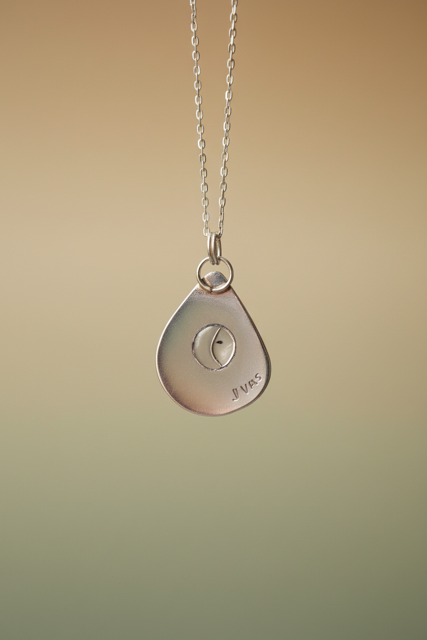 Silver necklace with a teardrop-shaped pendant on a beige background
