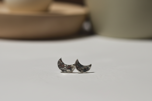 Crescent moon-shaped earrings on a neutral background