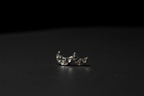 A pair of silver crescent moon stud earrings with a textured, hammered surface, displayed on a dark, reflective surface against a black background.
