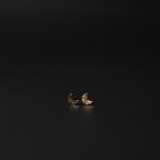 A pair of small crescent moon stud earrings in textured yellow gold, resting on a dark, reflective surface.