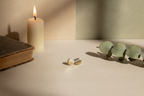 Gold earrings on a surface with a candle and green leaves in the background
