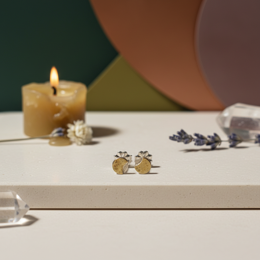 Pair of silver earrings with brass moons on a light gray background