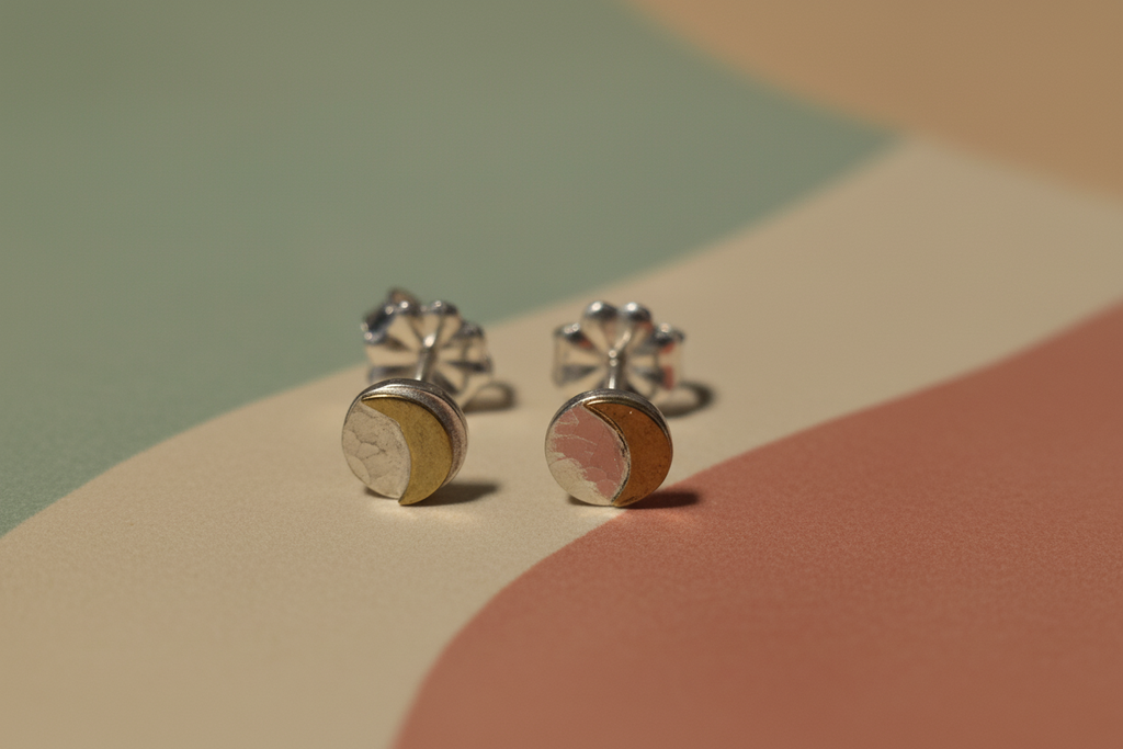 Pair of silver earrings with a gold accent on a multicolored background