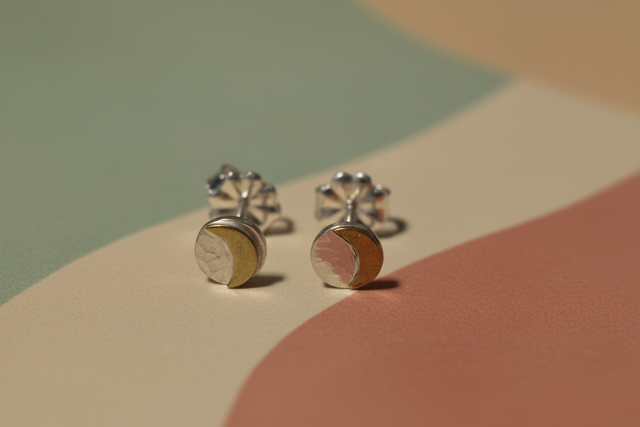 Pair of silver earrings with a gold accent on a multicolored background