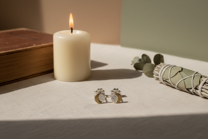 Pair of silver and gold round stud earrings on a light gray background