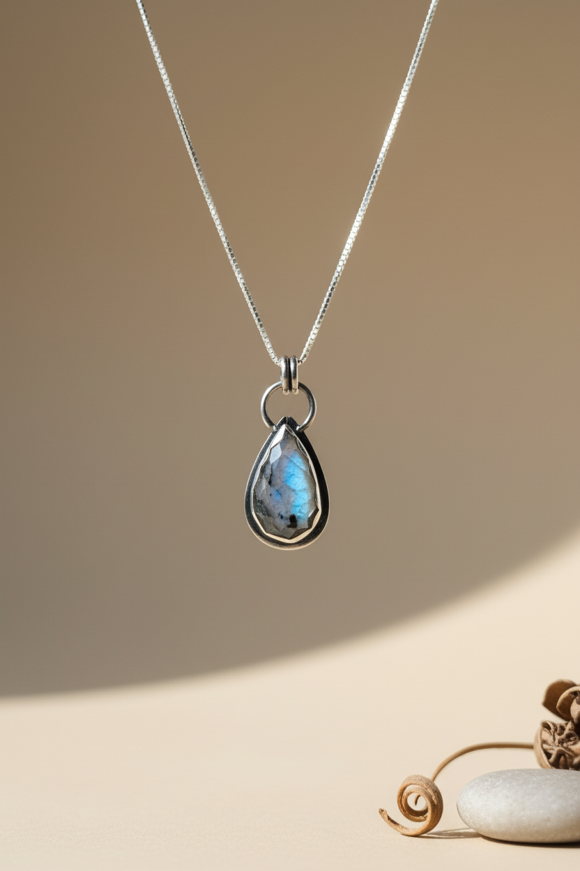 Teardrop-shaped pendant necklace on a beige background