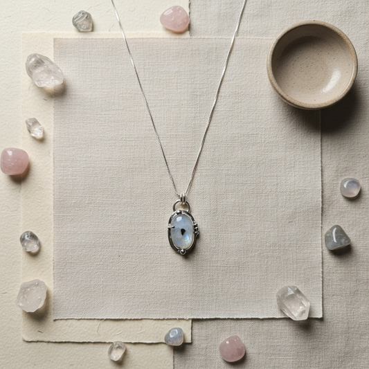 Necklace with a pendant on a textured surface surrounded by crystals