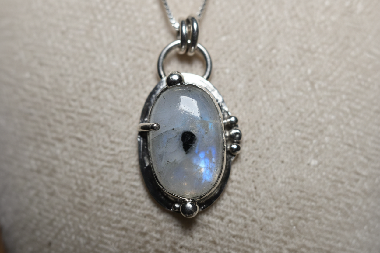 Silver pendant with a central gemstone on a neutral background