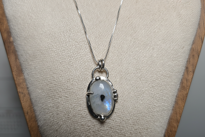 Silver pendant with a moonstone on a white stand