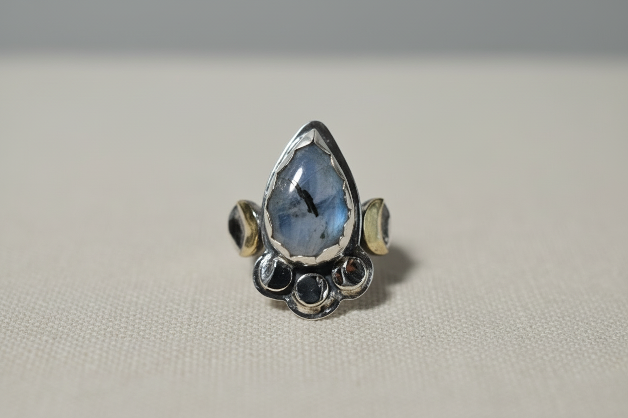 Silver ring with a teardrop-shaped blue gemstone on a light gray background