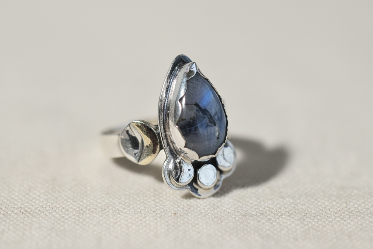Silver ring with a blue gemstone on a beige background