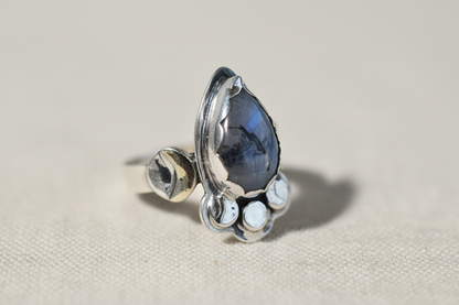 Silver ring with a blue gemstone on a beige background