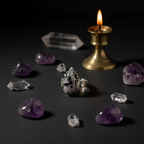 A silver ring with a black and white spotted owl face design, displayed on a dark surface surrounded by purple crystals, clear quartz points, and a lit brass candlestick.
