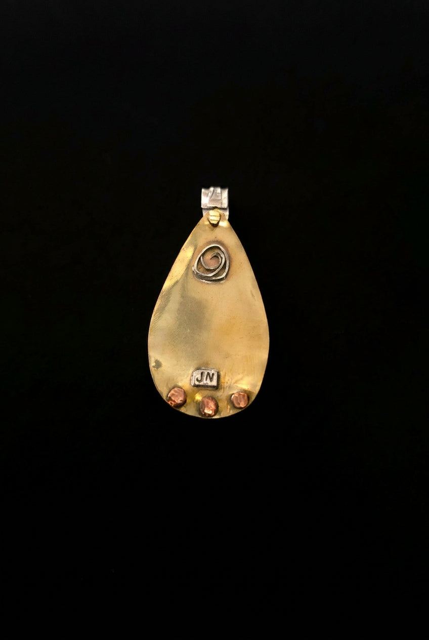 A teardrop-shaped gold pendant with a small silver bail, featuring a spiral design in the center and small red and white accents on the bottom right, displayed on a dark surface.