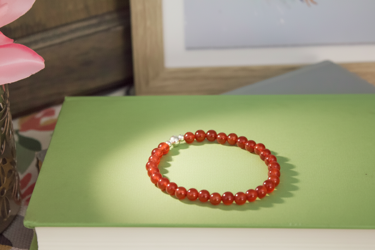 Red beaded bracelet on a green surface with a blurred background