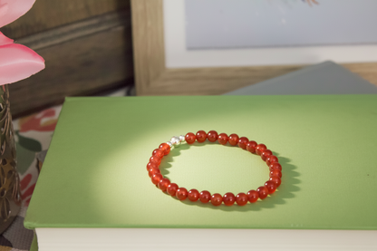 Red beaded bracelet on a green surface with a blurred background