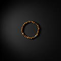 A beaded bracelet made of round brown and gold tiger's eye beads with a small silver spacer bead, displayed on a dark textured background.