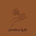 Illustration of a hand holding crystals with 'Jewellery by JN' text on a brown background
