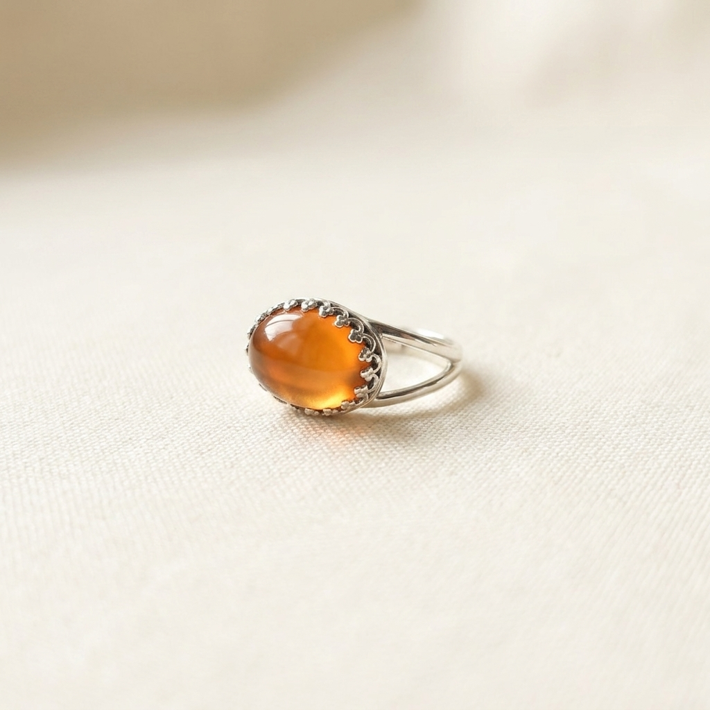 Silver ring with a large amber stone on a light fabric background