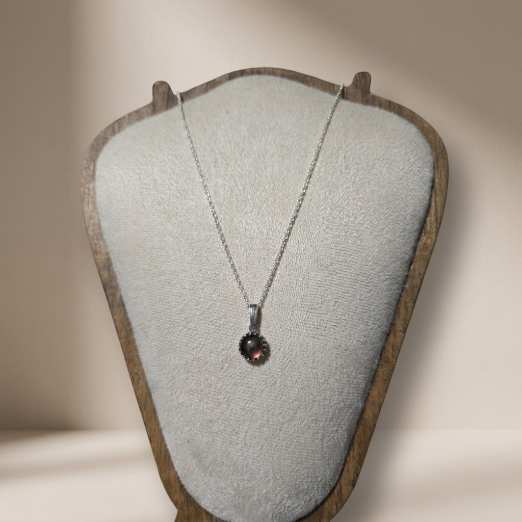 Necklace with a pendant on a textured display stand against a neutral background