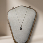 Necklace with a pendant on a textured display stand against a neutral background