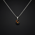 A silver chain necklace with a round pendant featuring a dark brown tiger's eye stone in a silver bezel setting, displayed against a dark textured background.