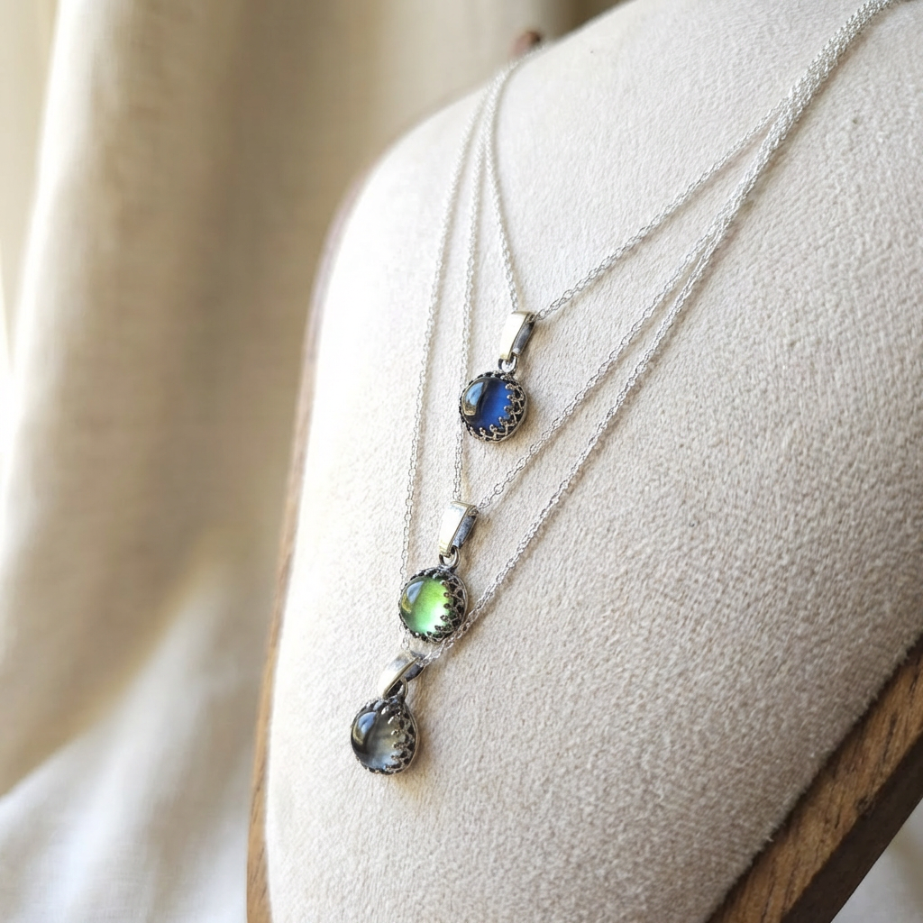 Two silver necklaces with pendant stones on a neutral background