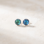 Pair of blue round stud earrings on a light beige background