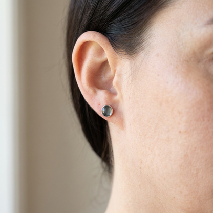 Close-up of an ear wearing a small stud earring with a neutral background