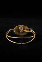 Inside back view of a handcrafted mixed-metal oval bangle bracelet showcasing the patinated brass backplate, stamped maker's mark, and silver clasp wire connections on a dark background.