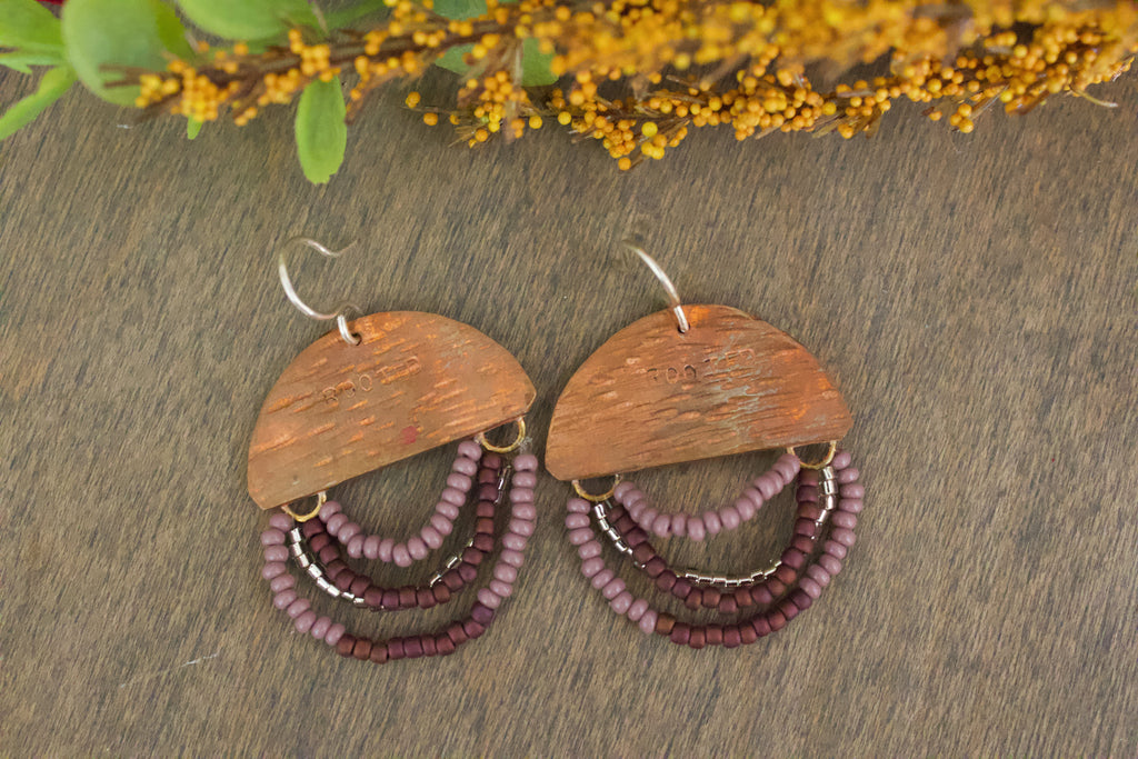 Close-up of Mini Wordkeeper Earrings Rooted by Jewellery by JN, highlighting textured copper, matte copper, coffee, and silver beadwork, and hand-stamped word ROOTED.
