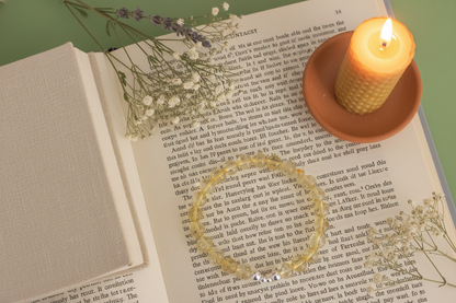Open book with a ring on top, surrounded by flowers and a lit candle.