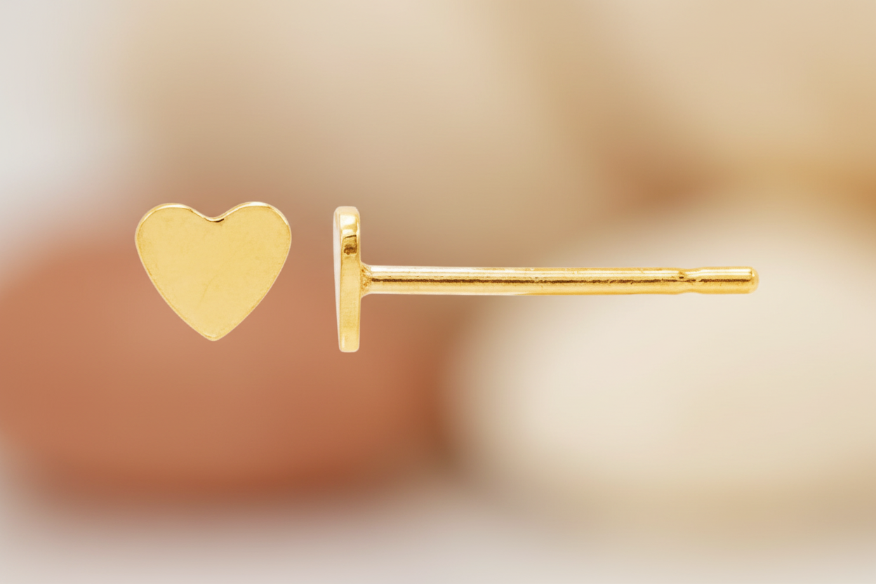 Gold heart-shaped earring on a blurred background