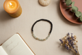 Shadowseer Bracelet by Jewellery by JN, featuring labradorite, volcanic rock, and sterling silver beads, arranged in a flat lay on a neutral background.
