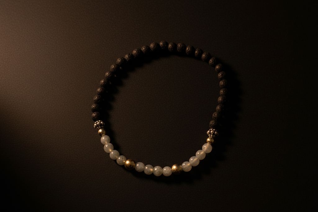 A beaded bracelet with dark brown and white beads separated by small gold spacer beads, displayed on a dark background.