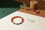 Multicolored beaded bracelet on a white surface with a card and candle in the background