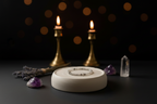 A delicate silver beaded bracelet rests on a round white ceramic stand, styled with purple crystals, dried lavender, and two lit brass candlesticks against a dark background with warm bokeh lights.