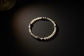 A beaded bracelet made of translucent white beads with small silver spacer beads, displayed on a dark background under warm spotlighting.