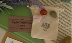 Love Gemstone Bag by Jewellery by JN, recycled cotton pouch with tumbled Carnelian, Rose Quartz, Clear Quartz, and Green Aventurine, displayed on creamy linen with ritual props.