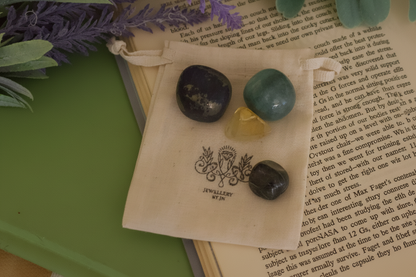 Three stones on a drawstring bag with a decorative emblem, placed on an open book.