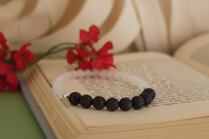Black beaded bracelet on an open book with red flowers in the background