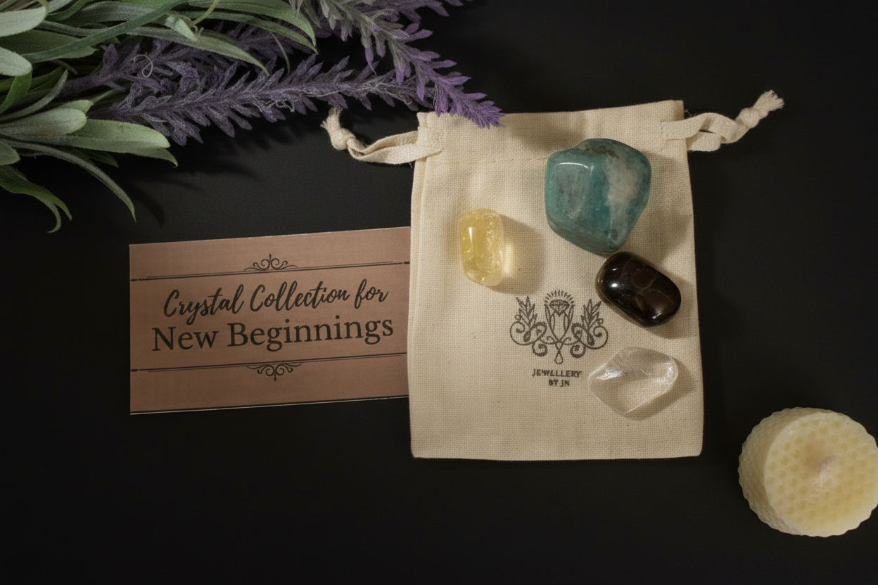 A crystal collection set displayed on a black background, featuring a cream canvas drawstring pouch with four polished crystals (teal, yellow, dark brown, and clear), a brown card reading 'Crystal Collection for New Beginnings', decorative greenery, and a white candle.