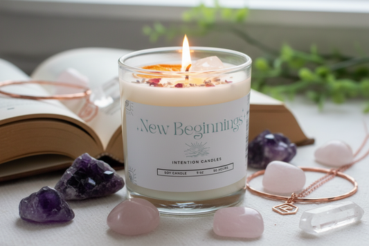 New Beginnings Intention Candle by Jewellery by JN, lit with glowing flame, showing Citrine and Clear Quartz crystals and botanicals embedded in wax.
