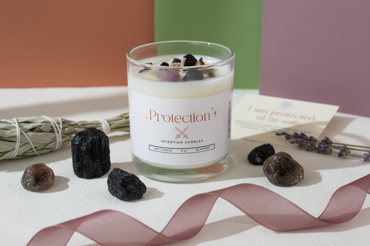 Protection Intention Candle by Jewellery by JN, hand-poured candle with Black Tourmaline, Obsidian, and Amethyst crystals, cinnamon bark, clove, cedar leaf, black pepper, and gold shimmer, displayed with ritual props.